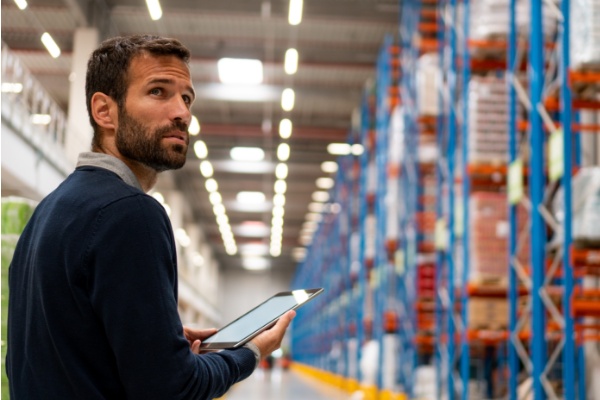 Man in warehouse holding a tablet.